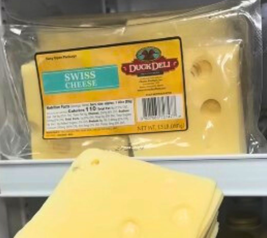 Packaged Swiss cheese with a Duck Deli label on a shelf.
