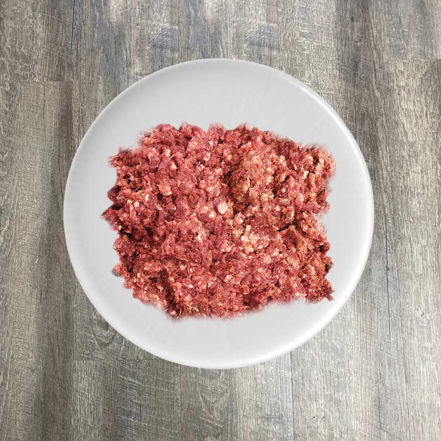 A plate of ground pork displayed on a wooden surface.