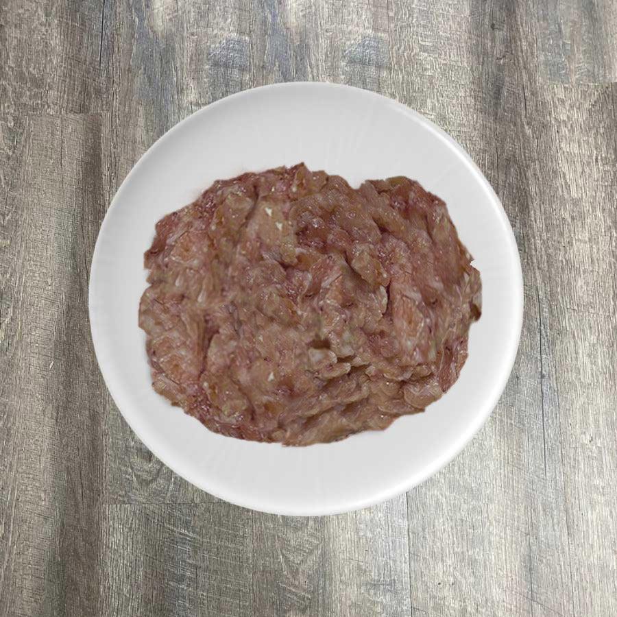 A plate with raw ground tuna on a wooden surface.