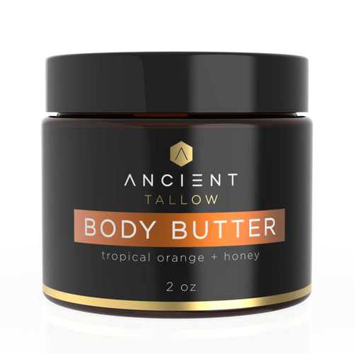 A jar of Ancient Tallow Body Butter with the label showing Tropical Orange & Honey. The jar is 2 oz and has a black lid and label with gold and orange text.