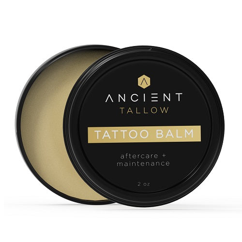 A jar of Ancient Tallow Tattoo Balm with aftercare and maintenance labels, showcasing a black lid and a gold-toned lid.