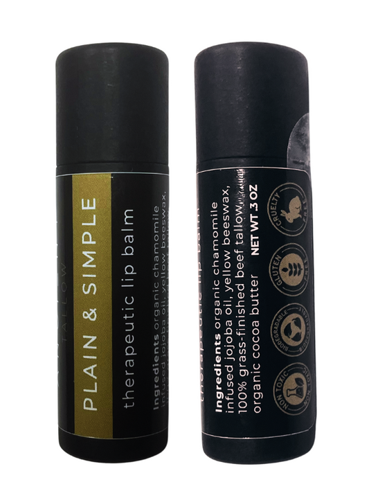 Two tubes of Ancient Tallow Therapeutic Lip Balm, one standing upright and the other lying down. The standing tube has a black and gold label, while the lying tube has a mostly black label with some text symbols.