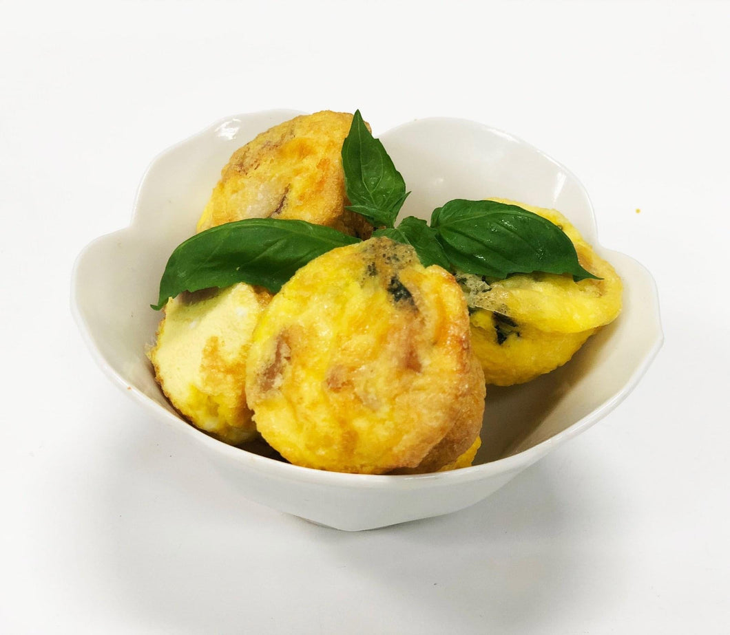 A bowl containing pieces of keto quiche, topped with fresh herbs.