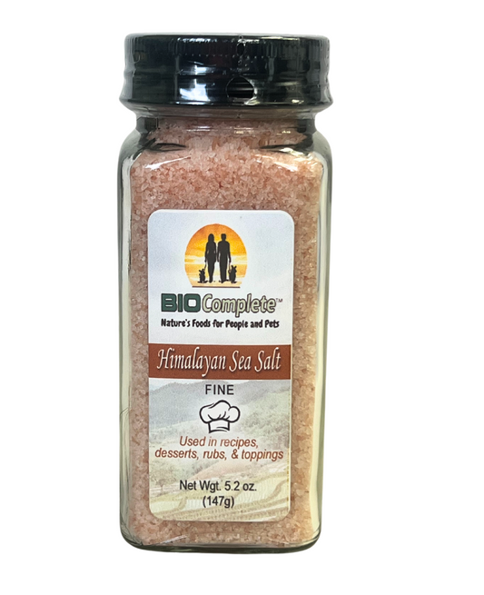 A clear plastic jar containing pink himalayan sea salt, with a label that includes the brand 'BioComplete' and information about the product.