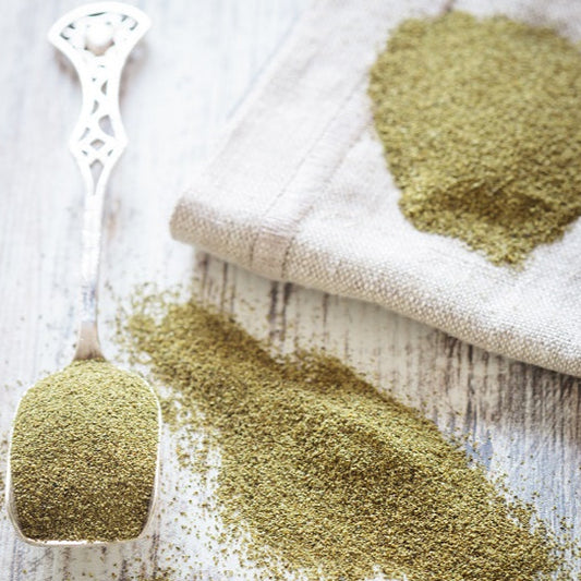 Green spice on a wooden surface with a cloth and measuring spoon.