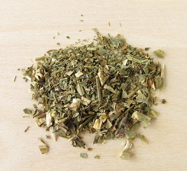 A pile of dried Lobelia herb leaves and flowers on a wooden surface.
