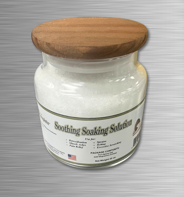 A clear glass jar with a wooden lid, labeled as 'Soothing Soaking Solution' containing white epsom salt.