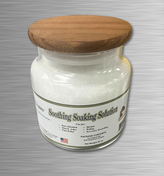 A clear glass jar with a wooden lid, labeled as 'Soothing Soaking Solution' containing white epsom salt.