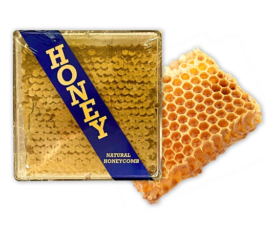 A large chunk of raw honeycomb with a golden color, next to a packaging box labeled 'HONEY' indicating the product is natural honeycomb.