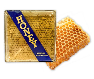 A large chunk of raw honeycomb with a golden color, next to a packaging box labeled 'HONEY' indicating the product is natural honeycomb.