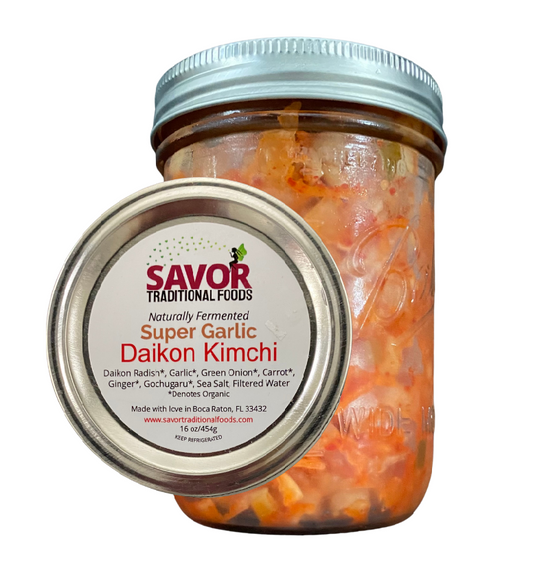 A jar of Savor Me Traditional Foods Super Garlic Daikon Kimchi. The jar is sealed and has a label displaying the product name and an image of the kimchi inside.