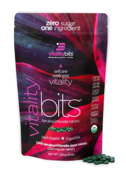 A package of VITALITYbits brand spirulina/chlorella tablets, with the product visible in a small pile in front of the package.