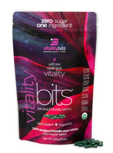 Load image into Gallery viewer, A package of VITALITYbits brand spirulina/chlorella tablets, with the product visible in a small pile in front of the package.