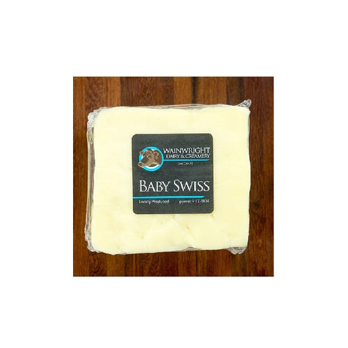 Packaged Wainwright Farm Organic Baby Swiss Cow Cheese on a wooden surface.