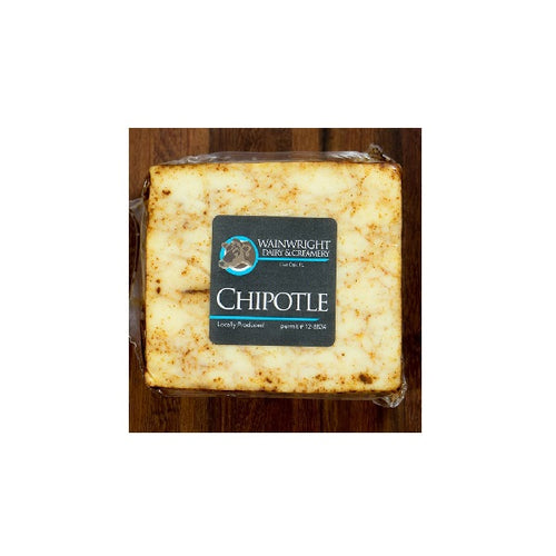Packaged cheese labeled 'Wainwright Organic Chipotle Cow Cheese' on a wooden surface.