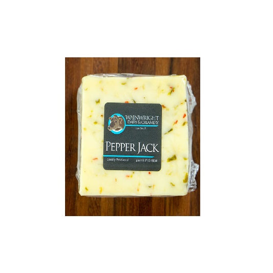 Packaged Wainwright Farm Organic Raw Pepper Jack Cow Cheese on a wooden surface.