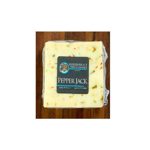 Packaged Wainwright Farm Organic Raw Pepper Jack Cow Cheese on a wooden surface.