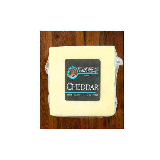 A block of white cheddar cheese with a label indicating it is organic and raw, from Wainwright Farm.