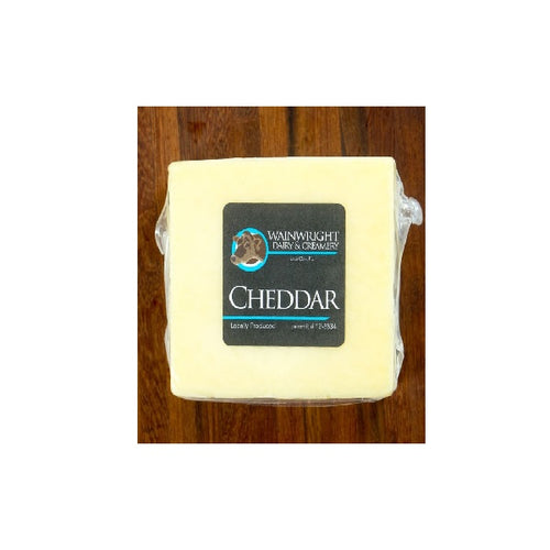 A block of white cheddar cheese with a label indicating it is organic and raw, from Wainwright Farm.