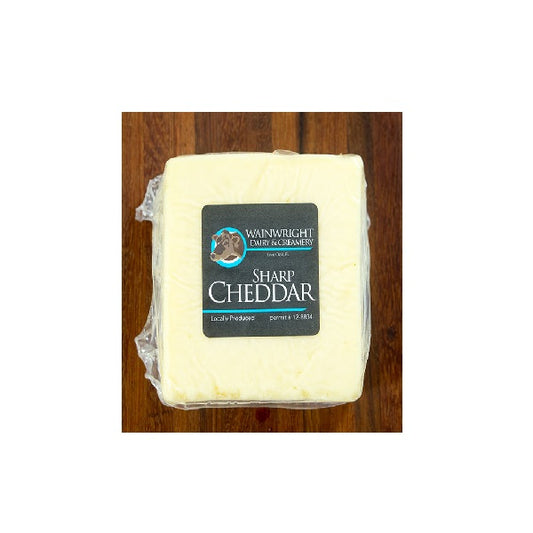 Packaged cheese labeled 'Sharp Cheddar' from Wainwright Farm on a wooden surface.