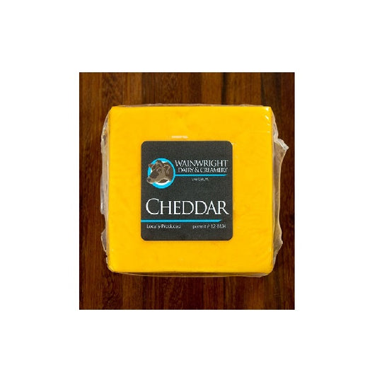 A block of yellow cheddar cheese with the label 'Wainwright' on it, placed on a wooden surface.