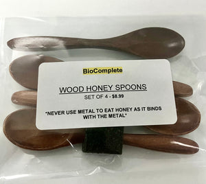 Packaged set of four wooden honey spoons with the brand label 'BioComplete' visible on the packaging.