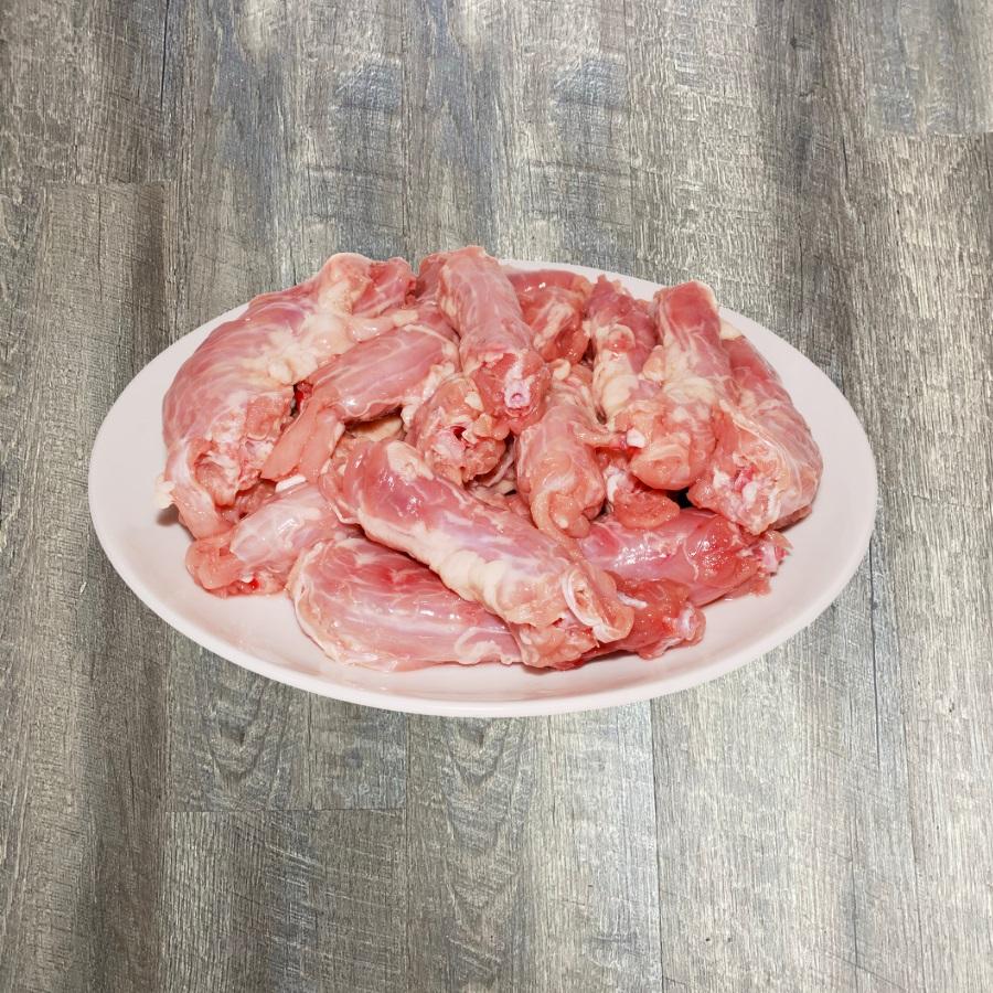 A plate of raw chicken necks on a wooden surface.