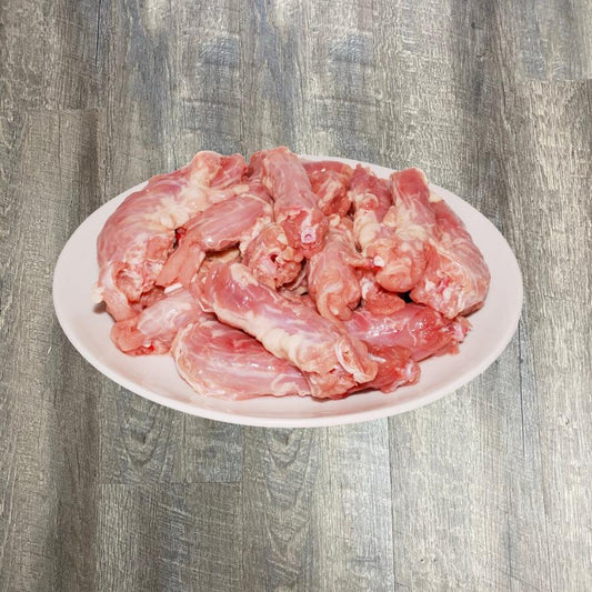 A plate of raw chicken necks on a wooden surface.