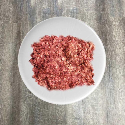 A plate of ground pork displayed on a wooden surface.