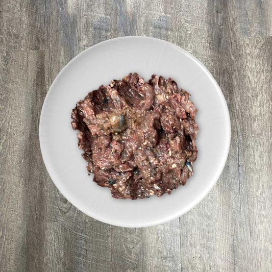 A bowl of ground sardine flesh on a white plate, placed on a wooden surface.