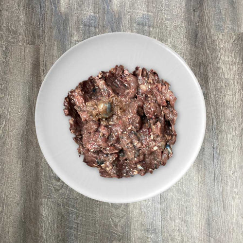 A bowl of ground sardine flesh on a white plate, placed on a wooden surface.