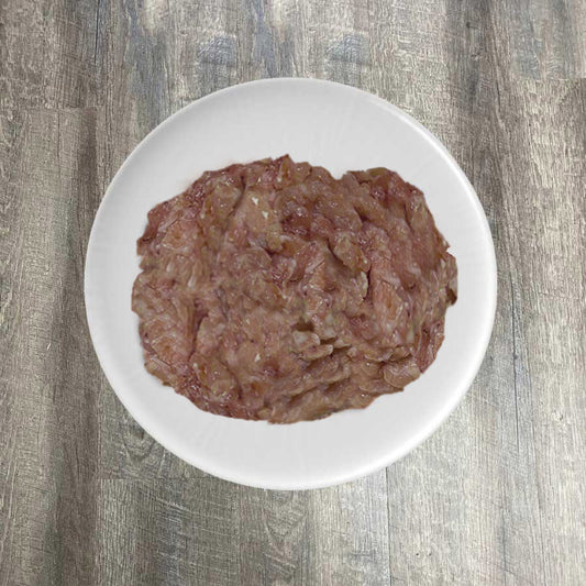 A plate with raw ground tuna on a wooden surface.