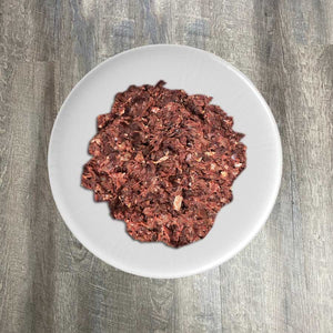 A plate of ground raw turkey meat displayed on a white plate against a wooden background.