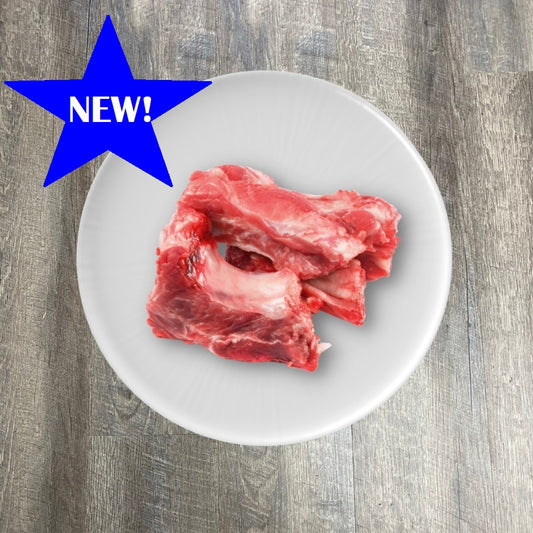 Raw pork rib bones on a white plate with a blue star label indicating 'NEW' on the top left corner.
